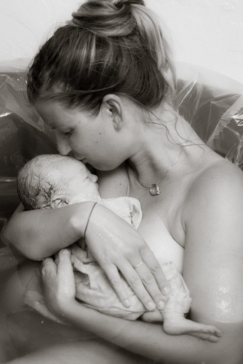 A Mom kisses her newborn baby boy after birthing him at home