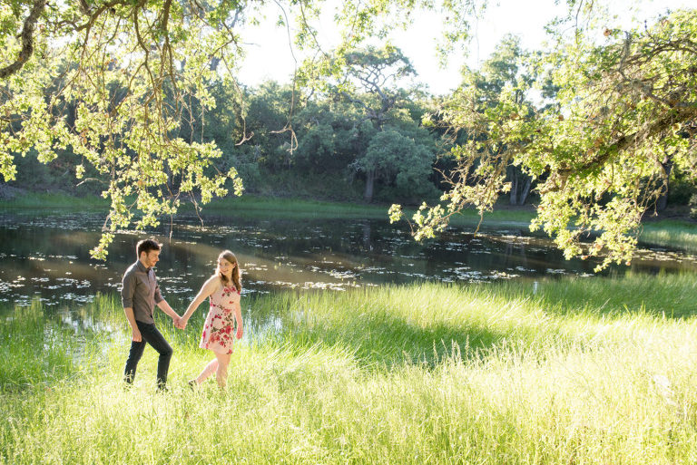 An engaged couple walls across a field 