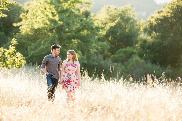 A couple walking in golden grass field.